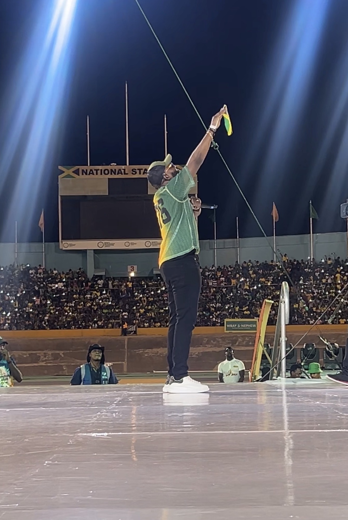 Kevin Downswell on stage at the National Stadium in Kingston, a Jamaican flag raised, the stands full